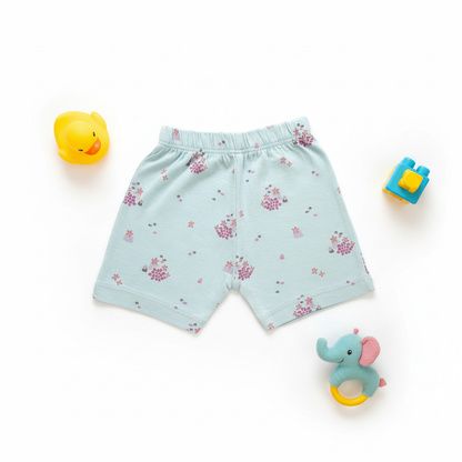 Light blue children's shorts with pink floral pattern on a white background with toys around